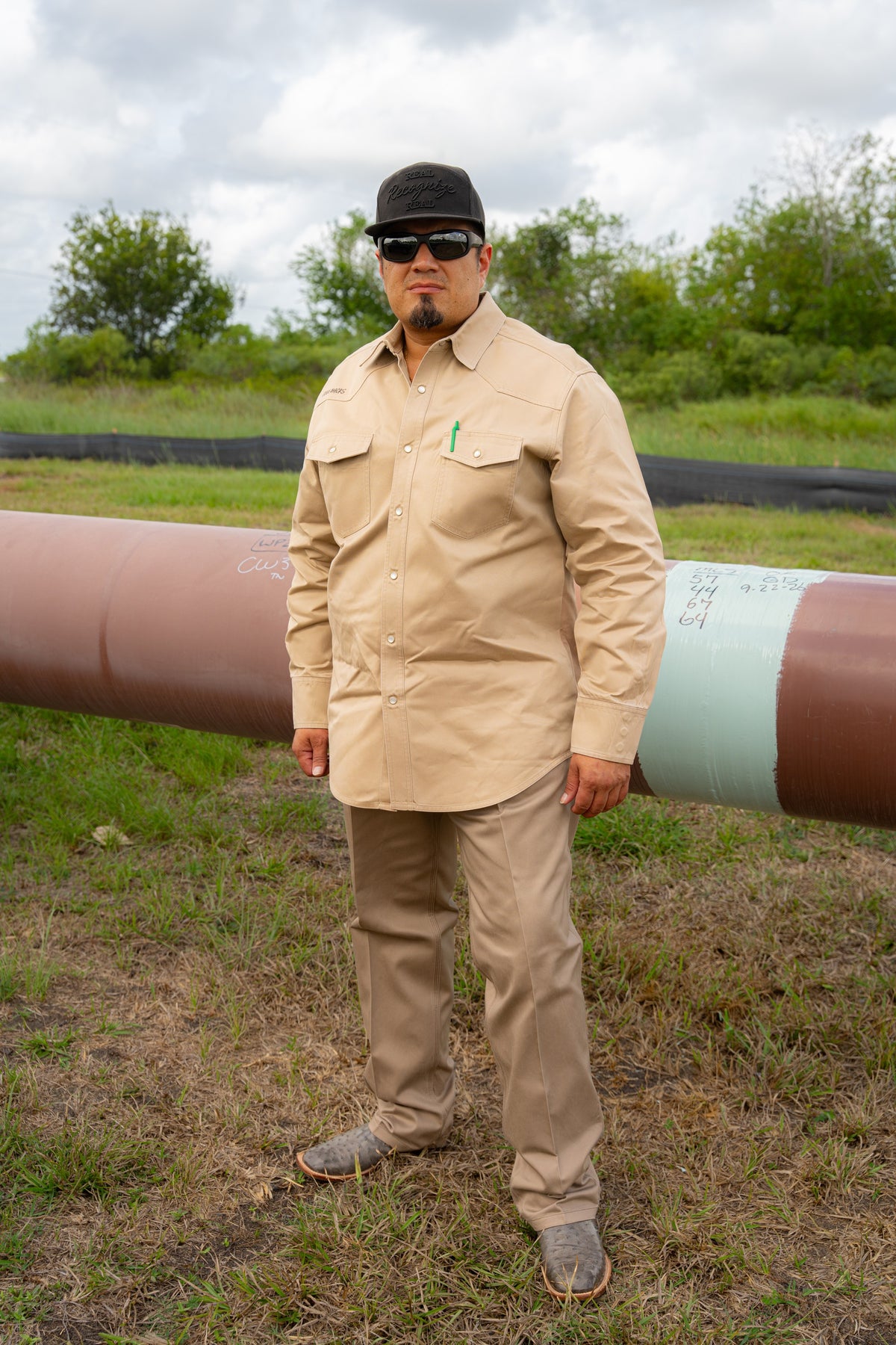 Welder wearing khaki FR COOLBACKS® Work Pants with a matching khaki work shirt at a pipeline job site