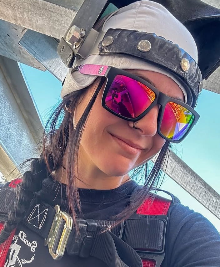 Person wearing a helmet and reflective sunglasses with a clear sky background
